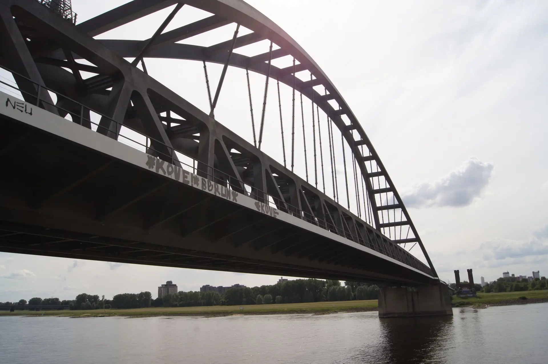 Blick von unten auf eine große geschwungene Eisenbahnbrücke, die über einen Fluss geht. Im Horizont des Bildes sieht man eine Stadt. Dieses Bild findet man auf der Webseite vom Bundesverband Burnout und Depression.