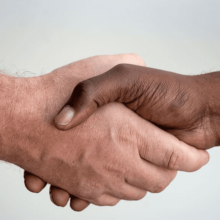 Eine helle und eine dunkle Hand greifen sich zum Händeschütteln vor einem grauen Hintergrund. Dieses Bild findet man auf der Webseite vom Bundesverband Burnout und Depression.